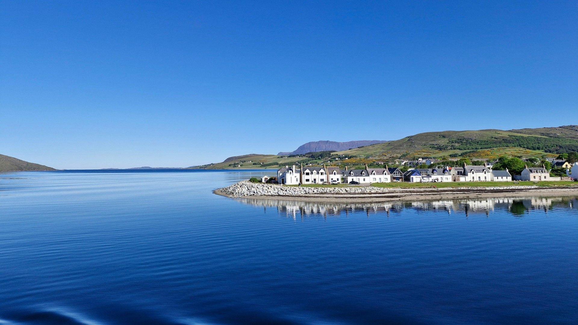 White fronted houses by a loch with blue skies overhead