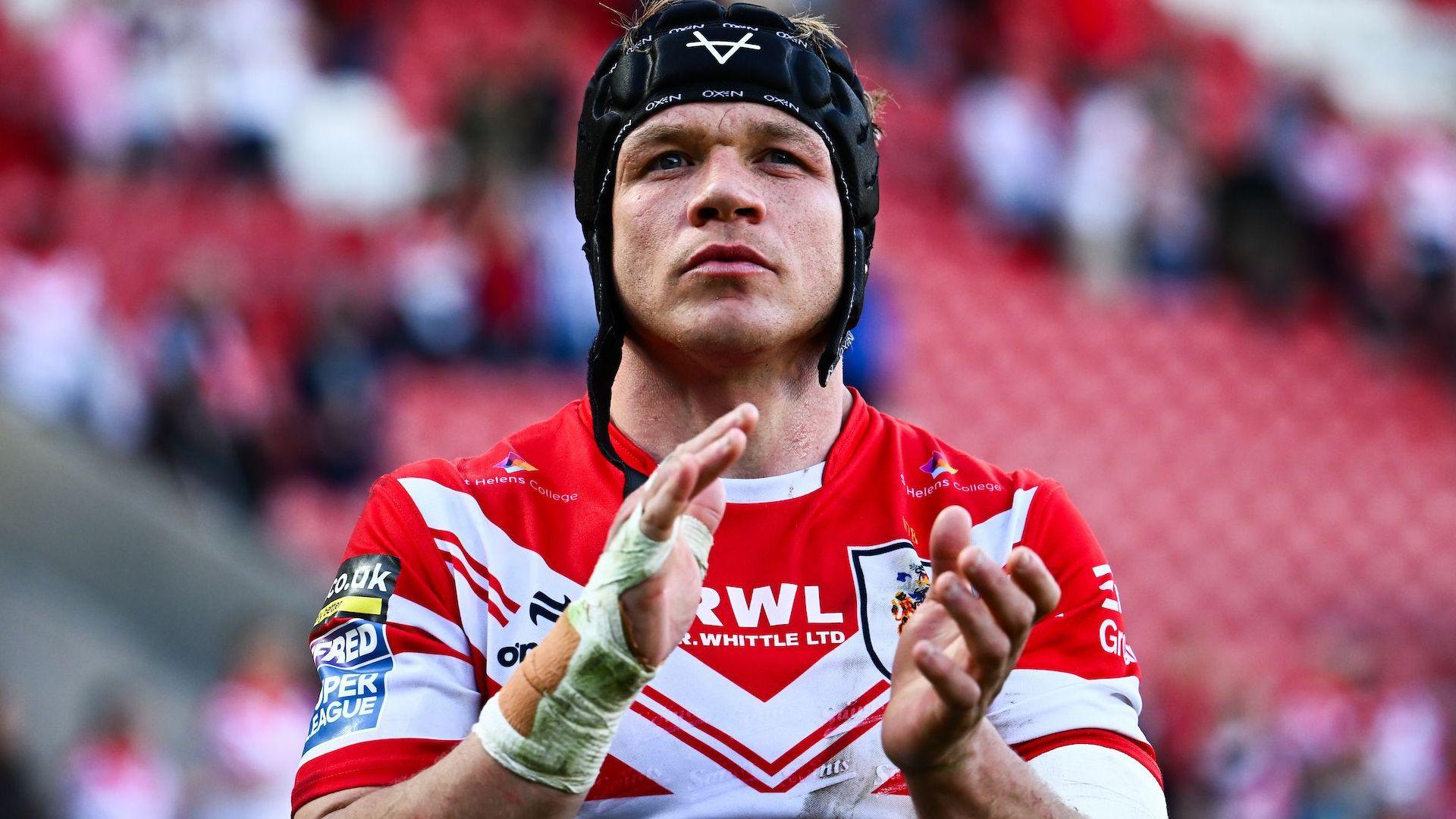 Jonny Lomax, wearing a trademark scrum cap with the chin strap undone, applauds the St Helens fans after a match