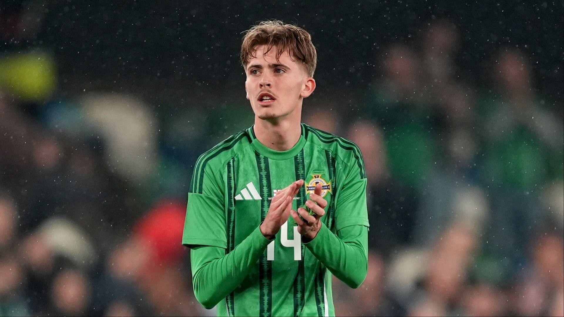 Isaac Price looks out to the crowd and claps wearing a green northern ireland kit