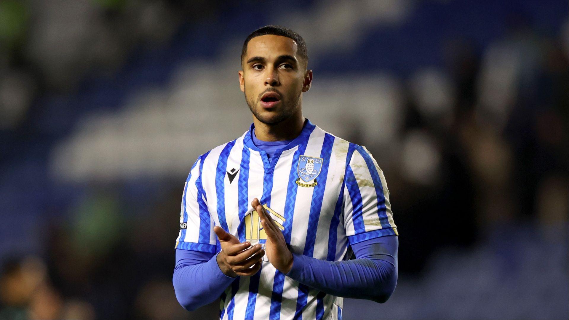 Defender Max Lowe wearing a blue and white striped Sheffield Wednesday shirt claps with a disappointed look on his face