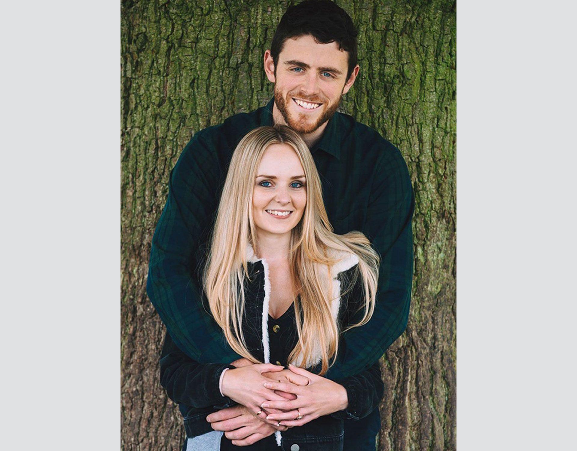 Police officer Andrew Harper, off duty, clasps his hands around his wife, Lissie, who puts her hands over his. They are both facing the camera, smiling. 