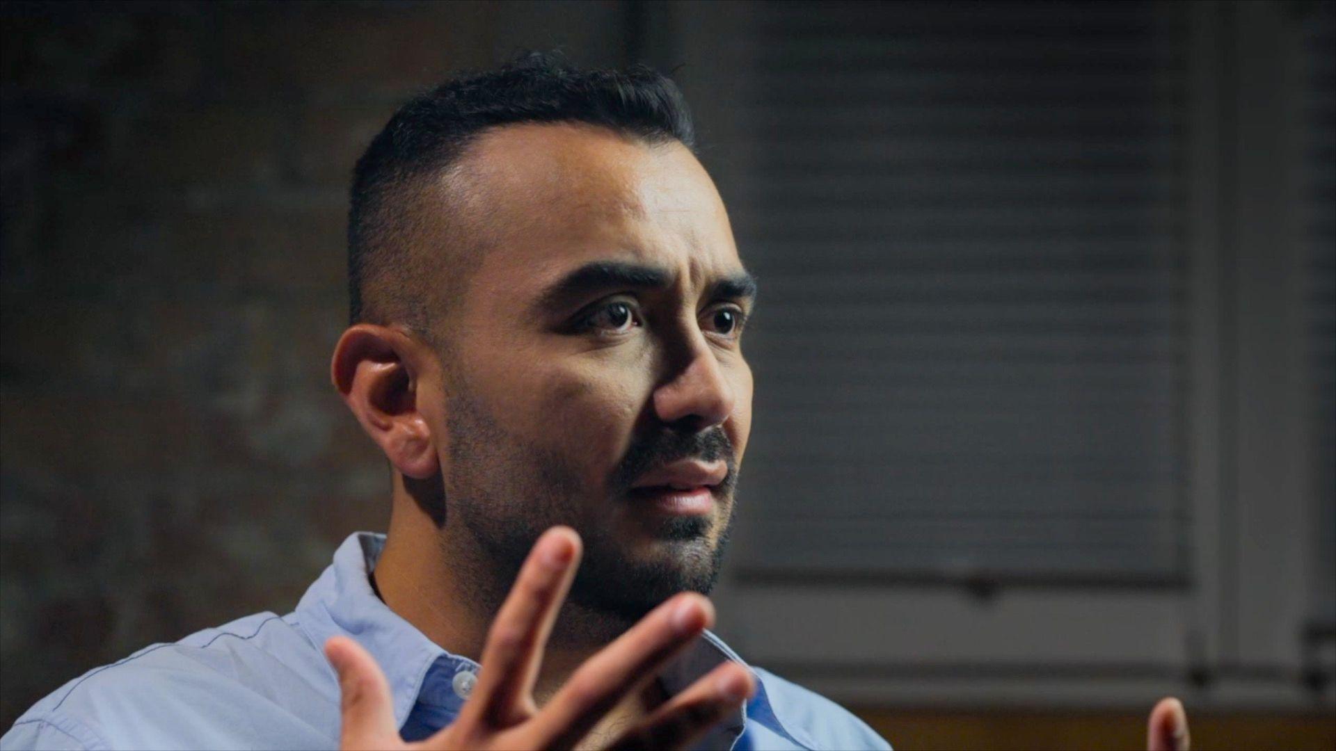 Mr Olarte wearing a blue shirt, with his hand outstretched in a gesture and a concerned expression, while speaking to the BBC