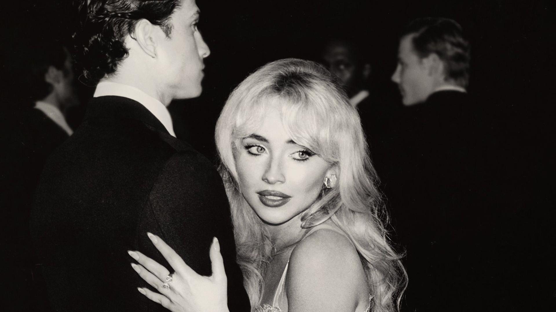 Black and white image of Sabrina Carpenter holding a man's arm