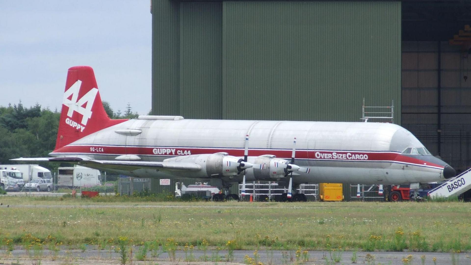 An old photo of the Conroy Skymaster painted in red and white livery with 44 Guppy painted on the tail and the registration of 9G-LCA.