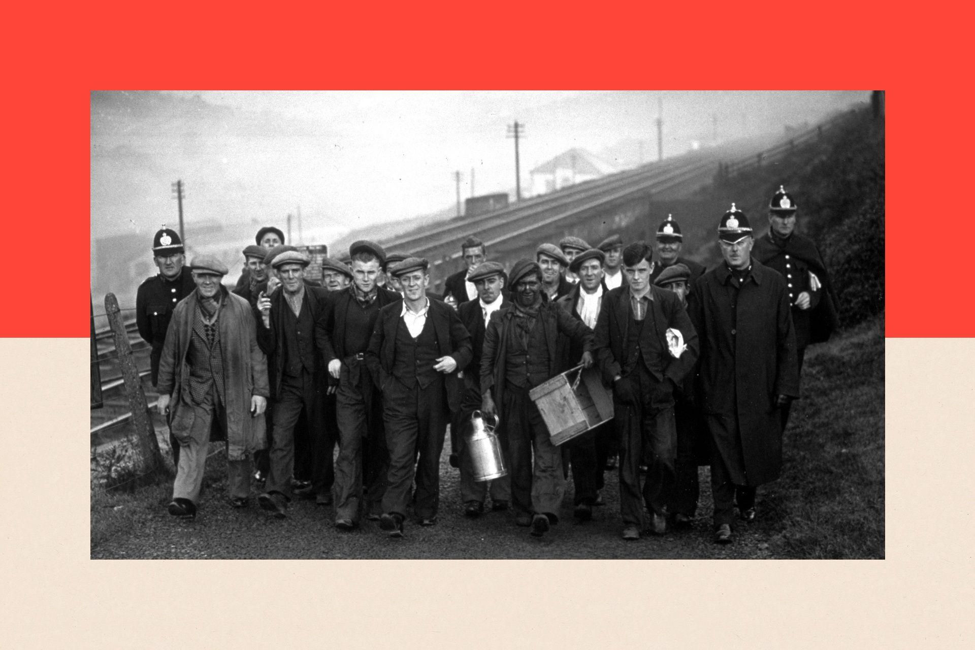 A black and white image of miners next to police leaving the Taff Merthyr pit having spent 24 hours on strike below ground