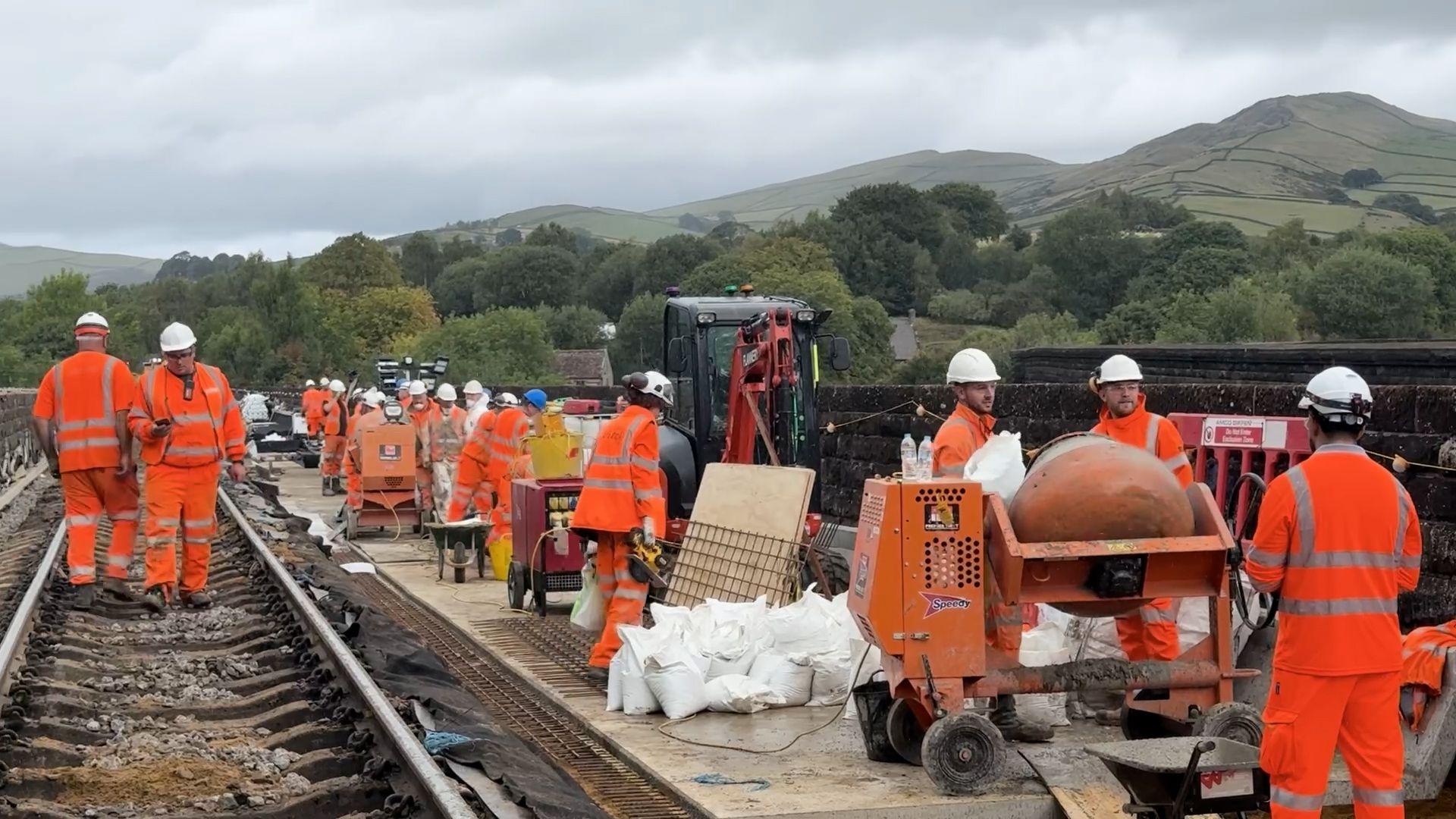 Workers in orange hi vis working on a Victorian viaduct in Chapel en le Frith
