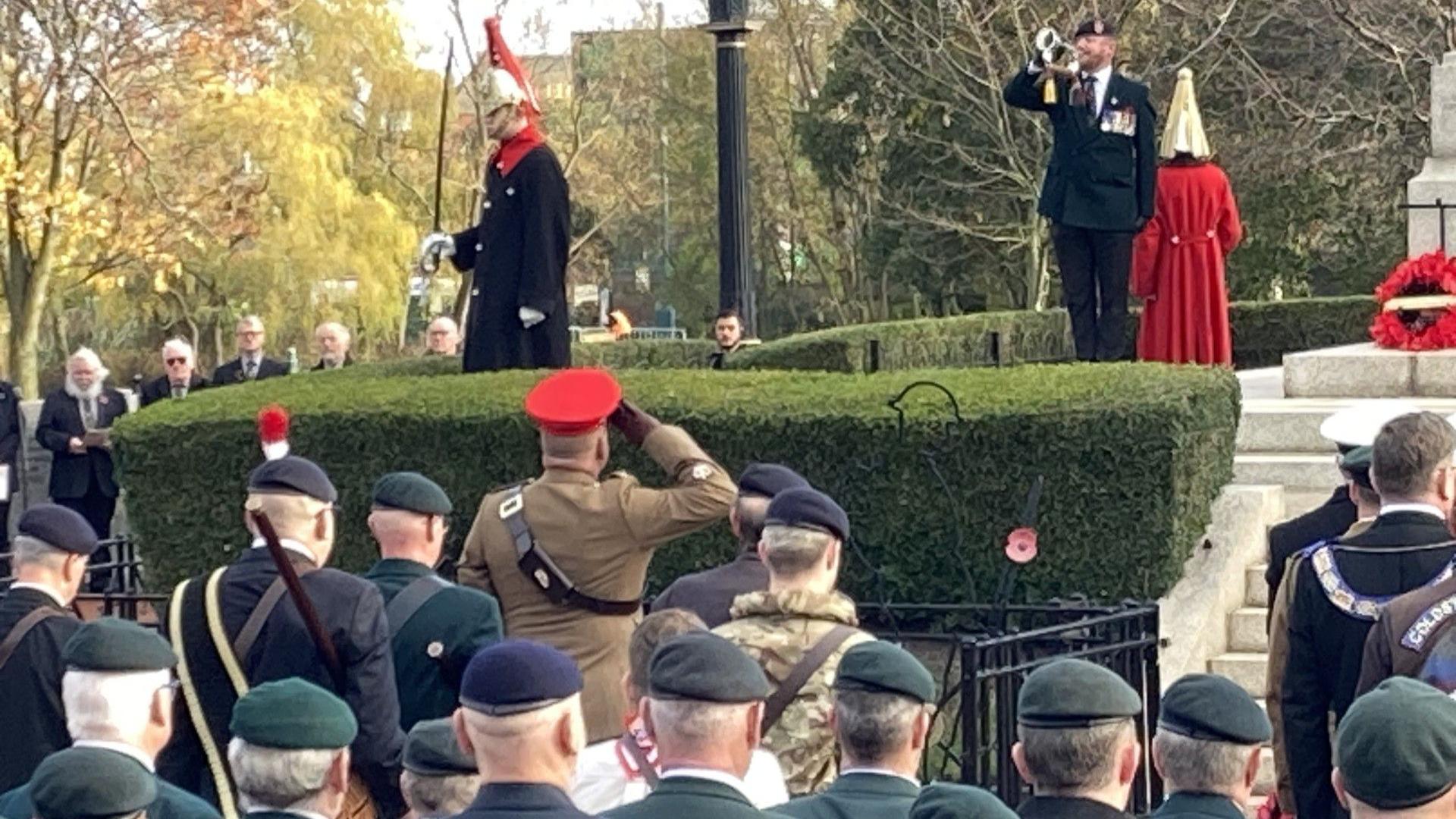 A trumpeter marks the minute's silence in Sunderland. An officer raises a salute while armed forces veterans pay their respects. An officer stands holding a sword near the cenotaph.