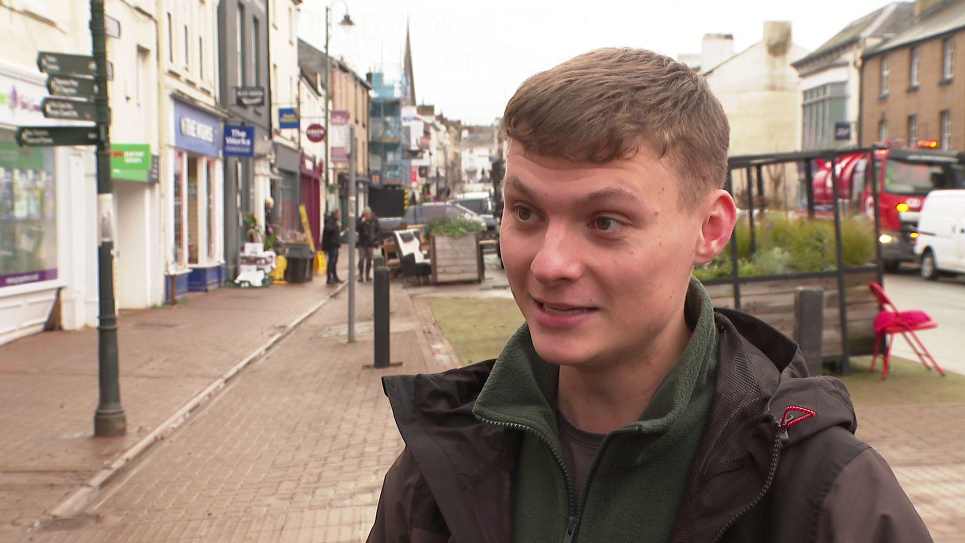 Adam Williams ar Stryd Fawr Trefynwy wrth i'r gwaith clirio fynd ymlaen o'w gwmpas