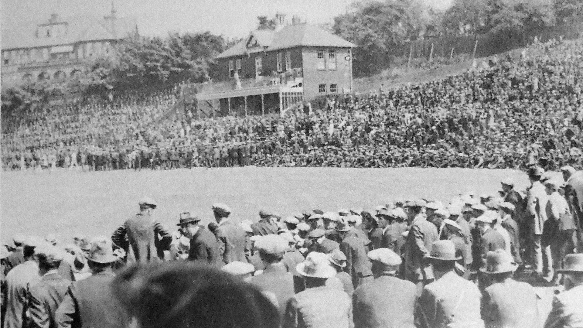 A black and white image from 1926 of thousands of men in caps and bowler hats looking over a cricket ground