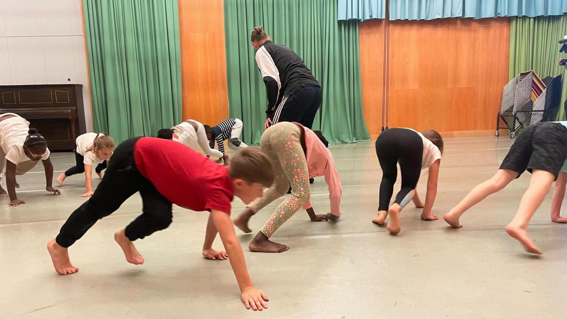 Children, dressed in casual clothes, move on all-fours around a dance studio