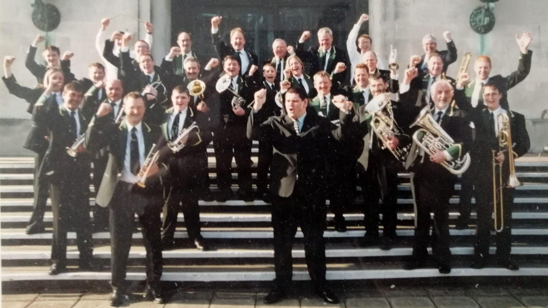 Gavin Saynor yn dathlu ennill ym Mhencamperiaethau Rhanbarthol Cymru yn 2003 fel arweinydd Seindorf Arian Llanrug