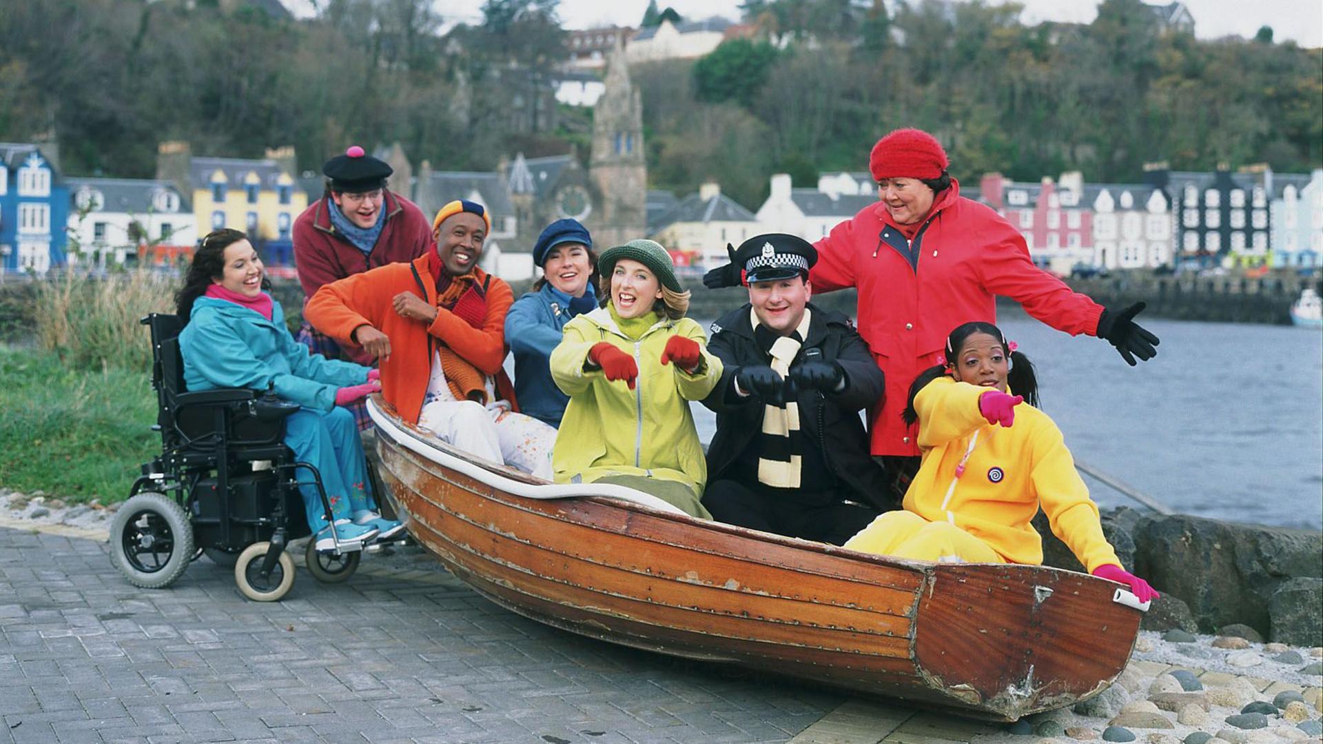 The original cast of Balamory smiling in a boat