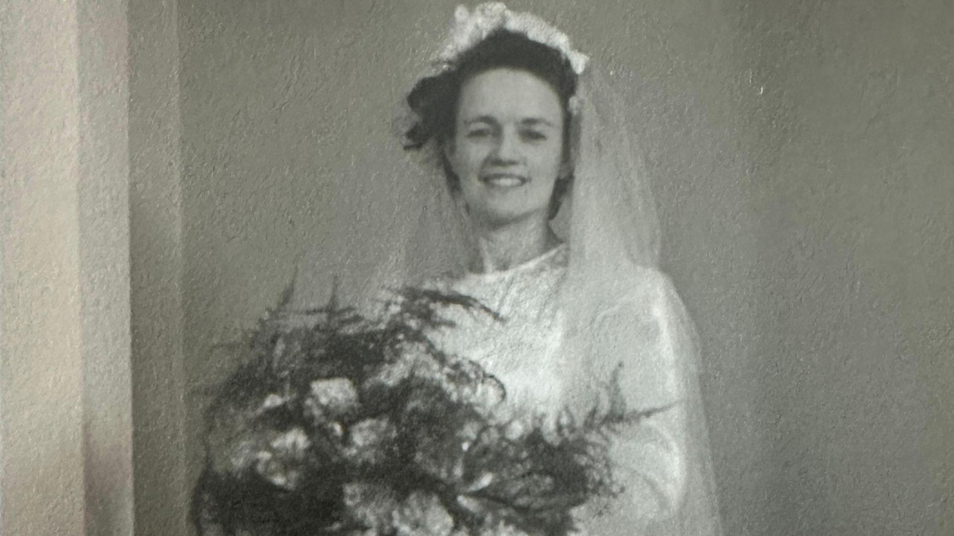 A woman in a white wedding dress holds flowers. It is Hilda Hutton who made munitions in Rotherham during wartime