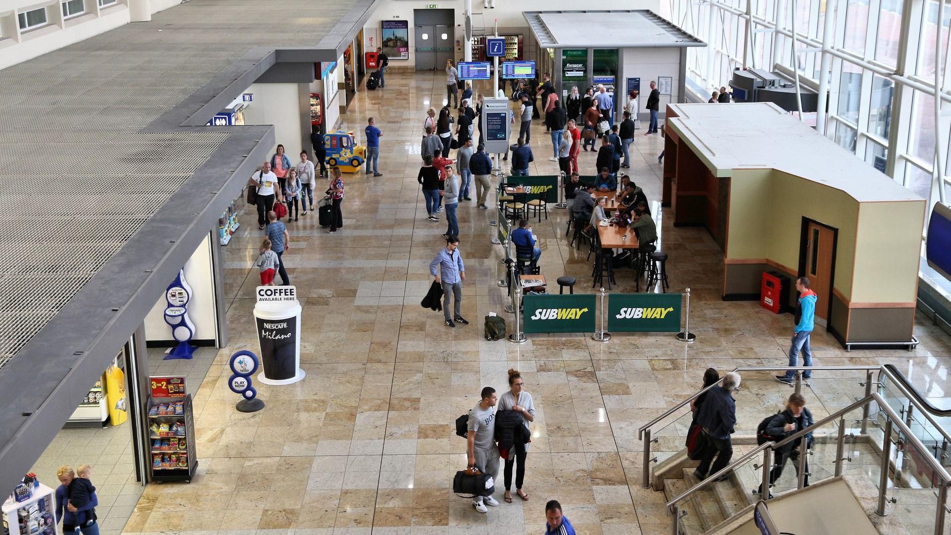 People mill around shops and food outlets at an airport terminal