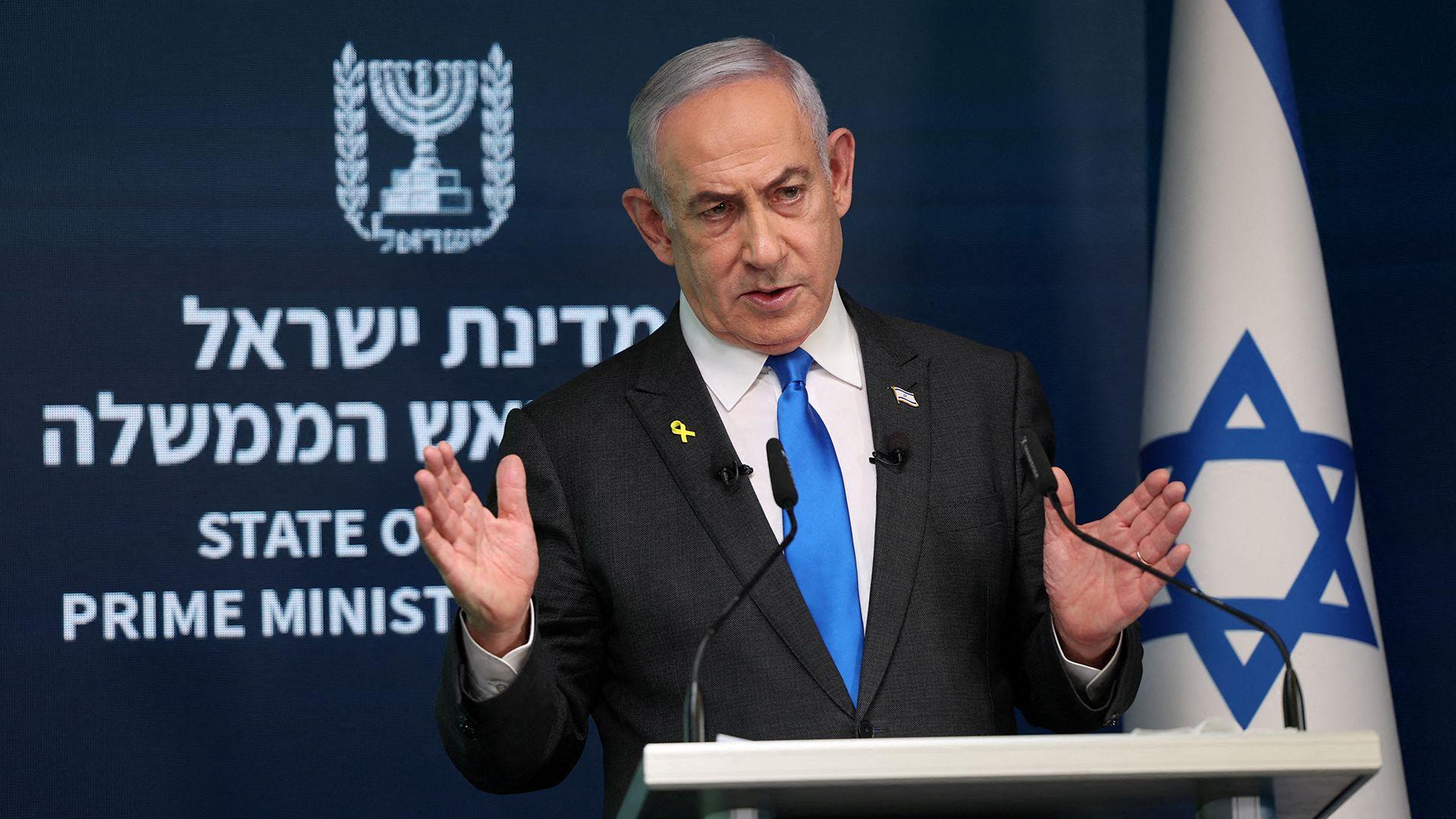 israel prime minister benjamin netanyahu speaking at a podium with an israeli flag next to him