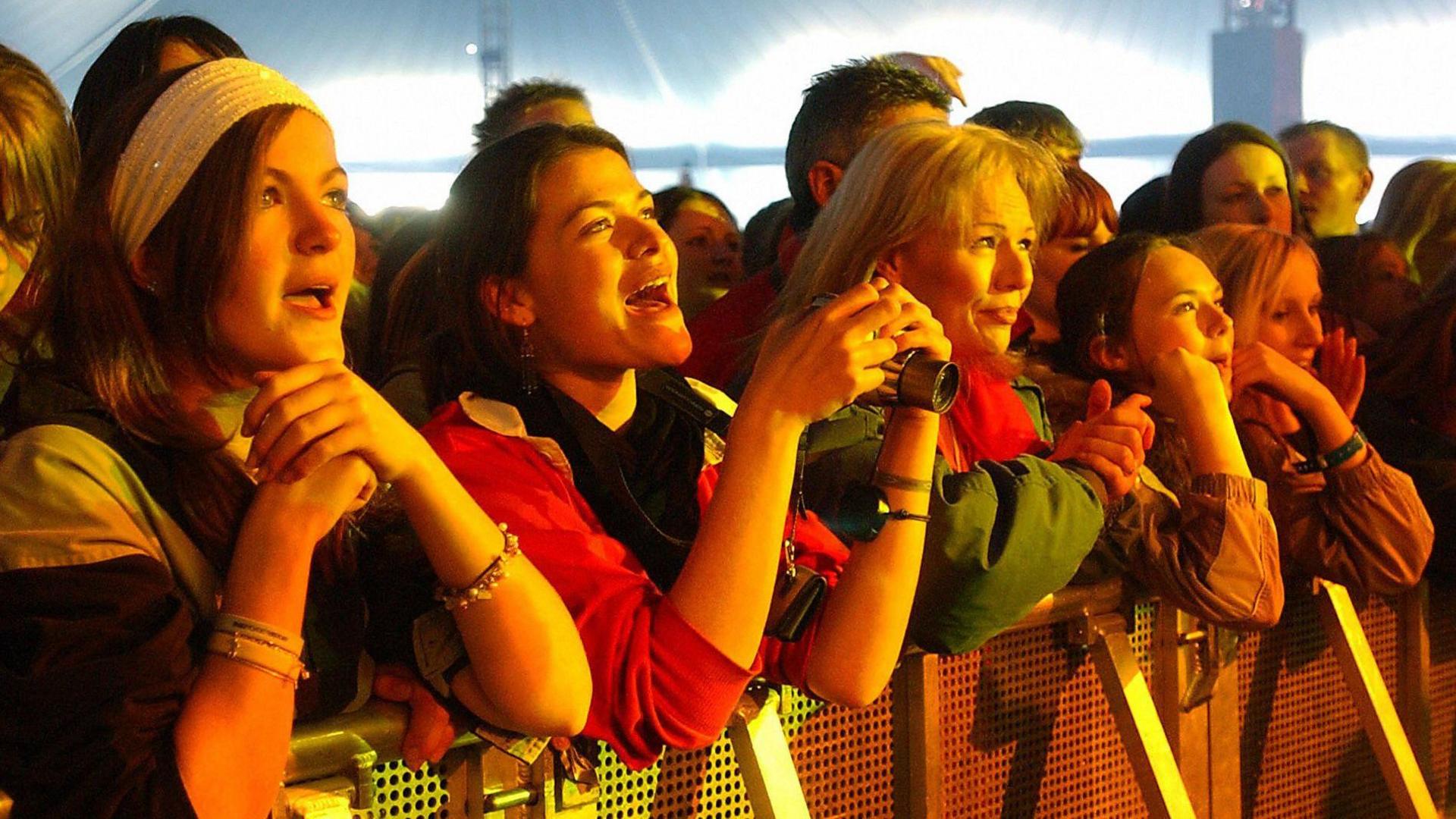 A group of women look at the stage and sing along.
