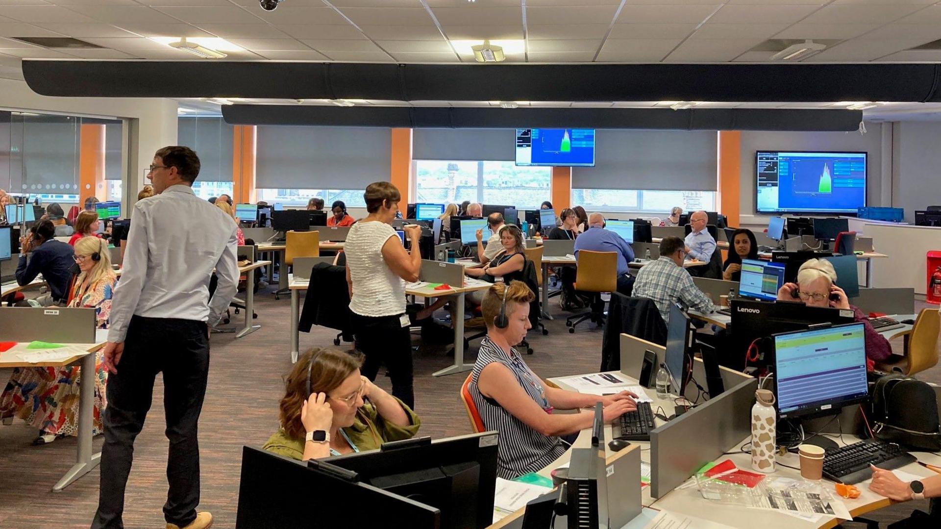 University staff wearing headsets and sitting at desks taking calls in a temporary call centre during this year's Clearing day at the University of Bradford