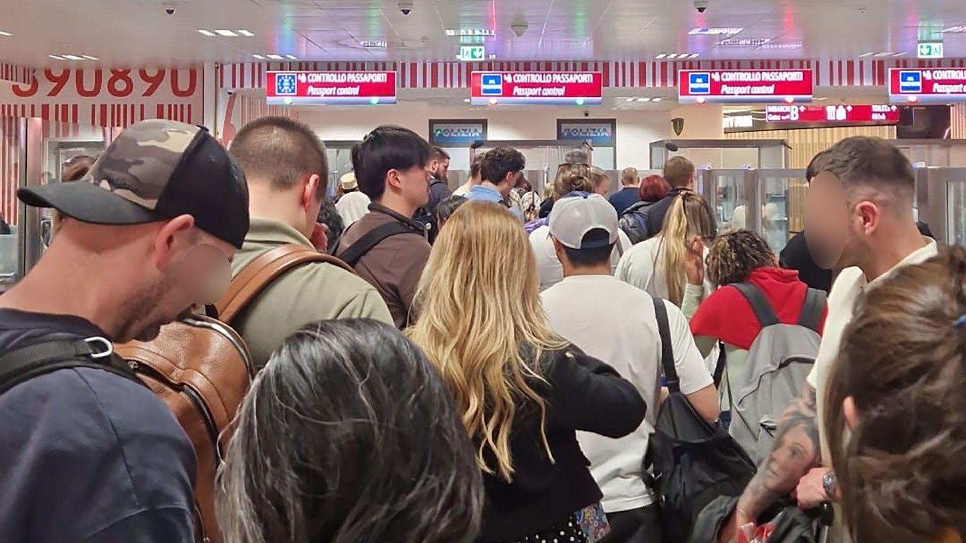 A crowd of passengers waiting in the passport control queue at Milan Bergamo airport on 16 April,  with four check-in desks visible.