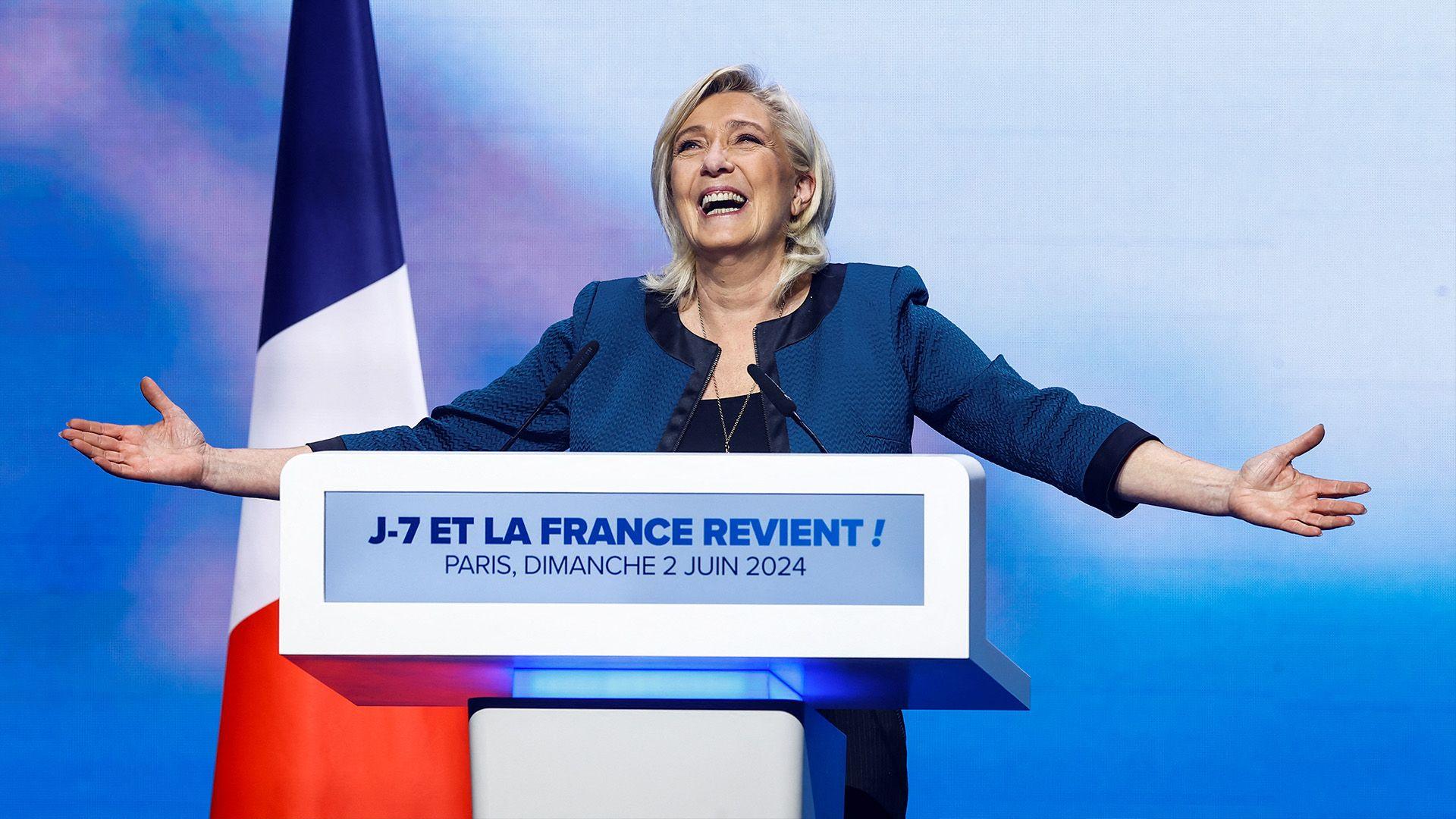 Marine Le Pen behind a lectern looking celebratory