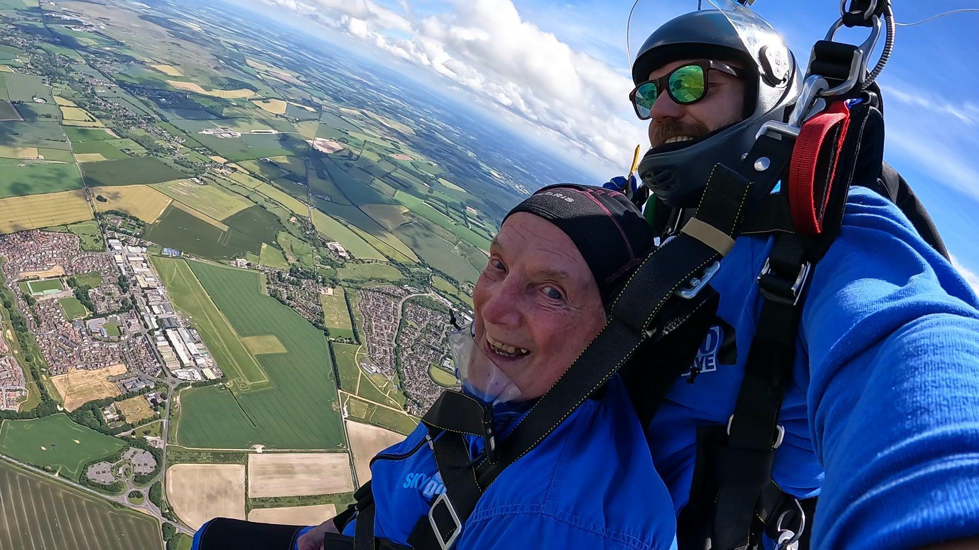 88-year-old James Mckellar strapped to his skydive instructor with a view of the ground 