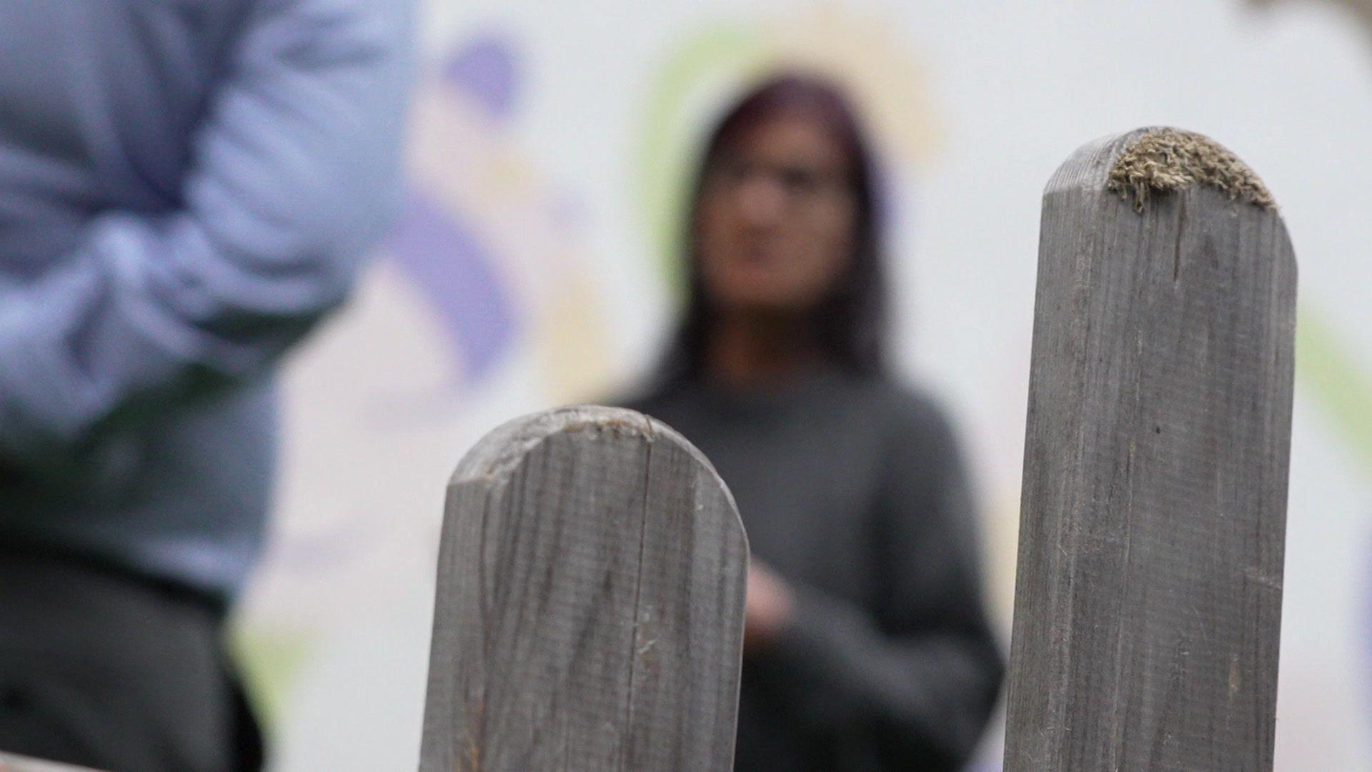 A blurry image of woman wearing a grey jumper.