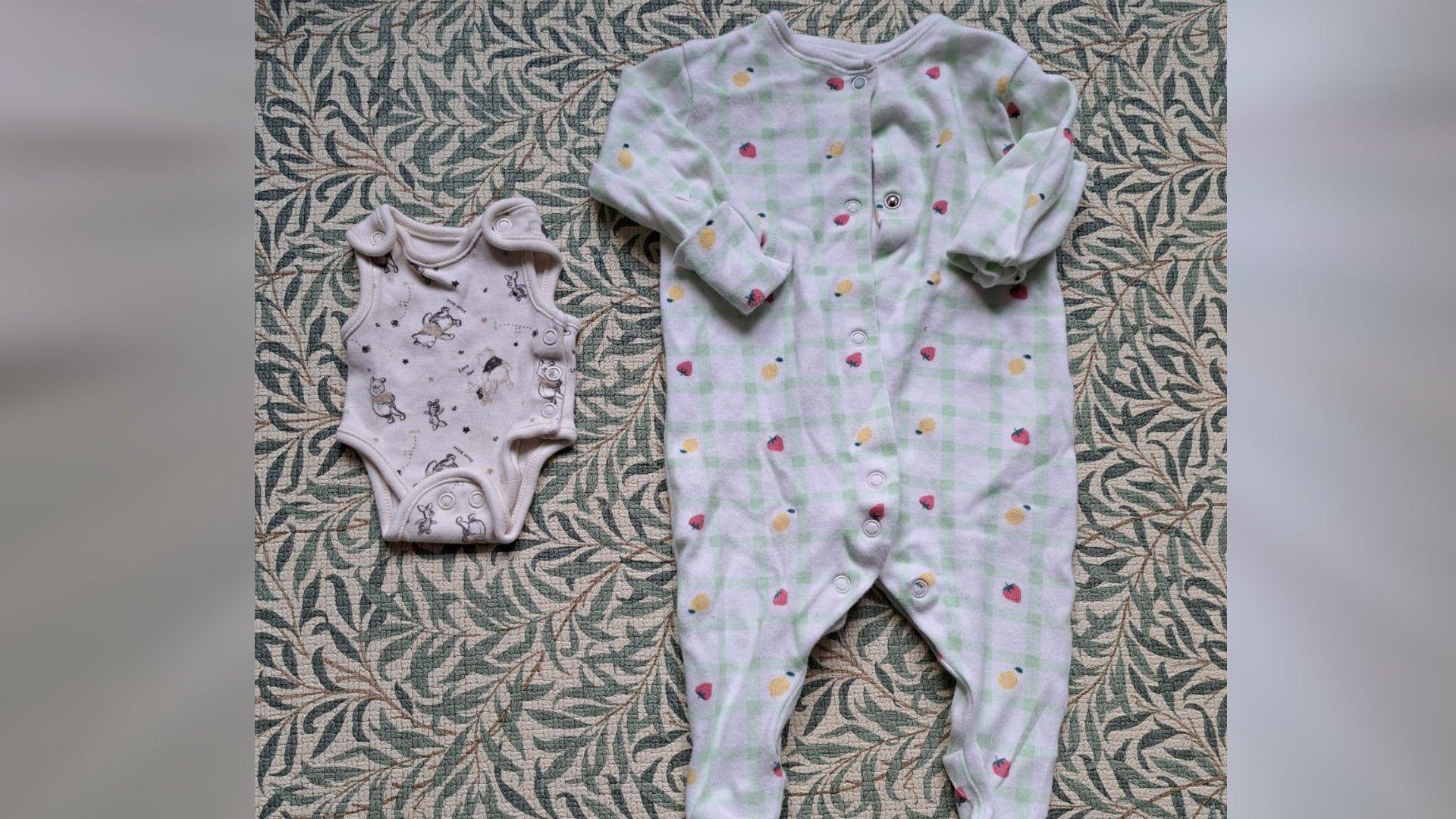 Two babygro outfits placed next to each other - one small white with teddy bears on it and another green and white checked with fruits on it