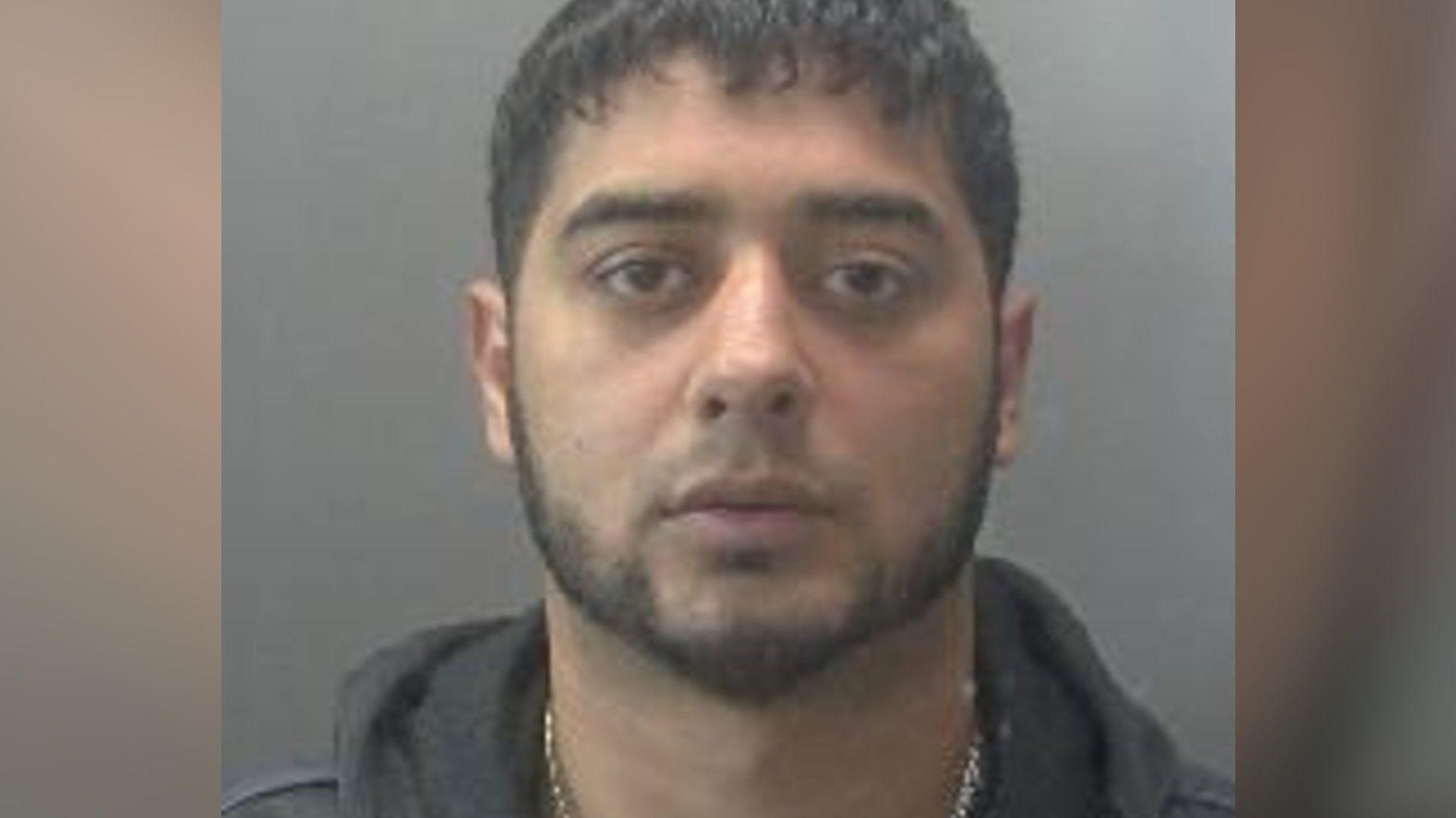 A custody image of a man wearing a grey hoodie.