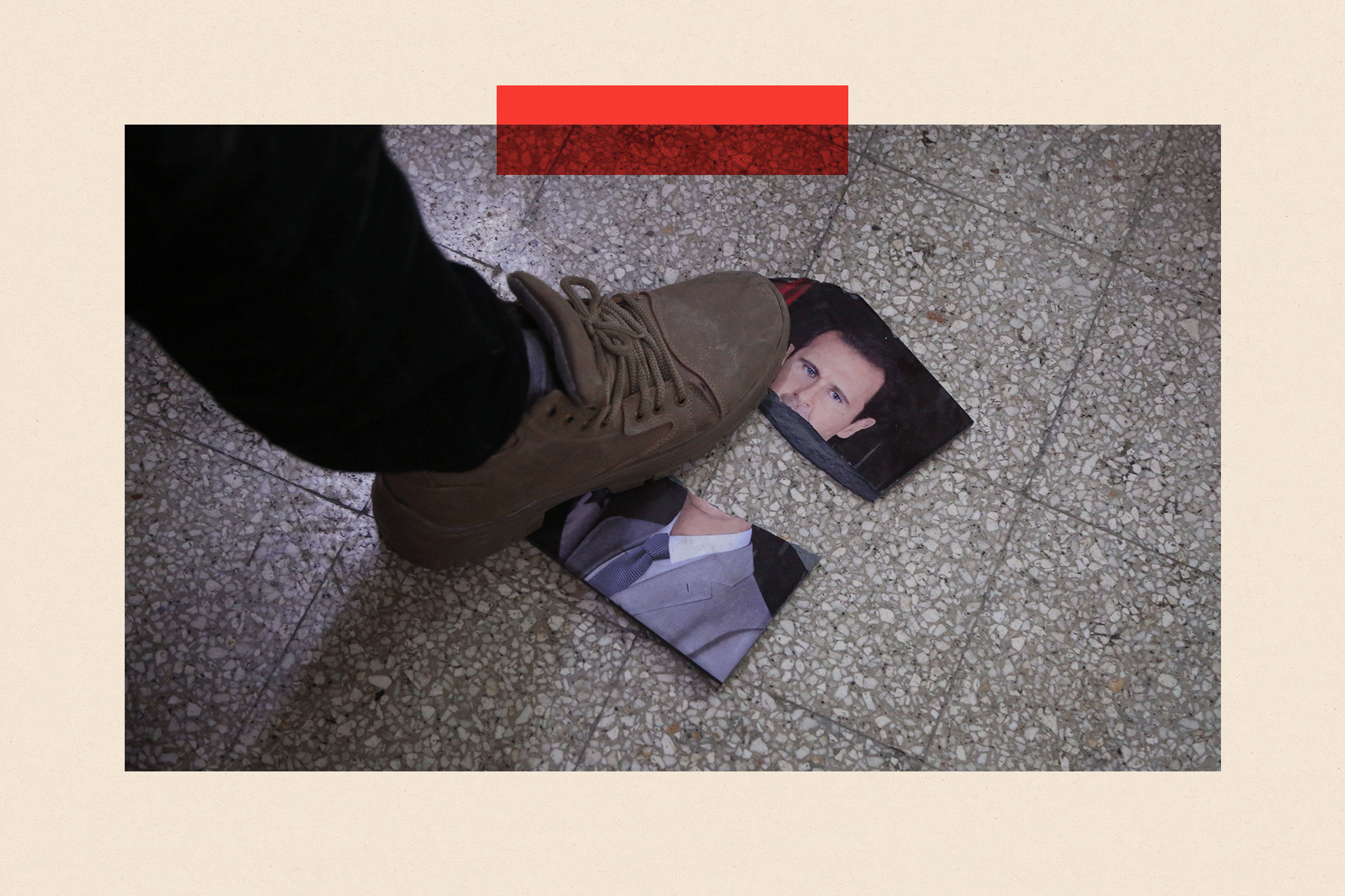 A person steps on a damaged portrait of Bashar al-Assad