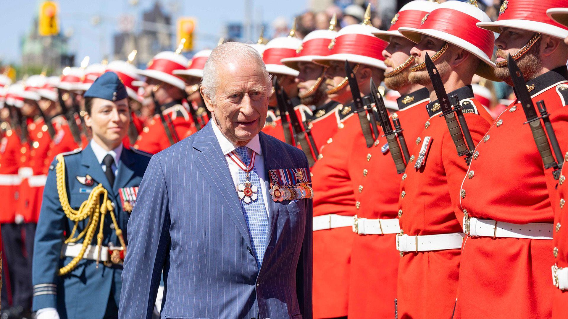 King Charles inspects Canadian troops dressed in traditional red and white uniforms.