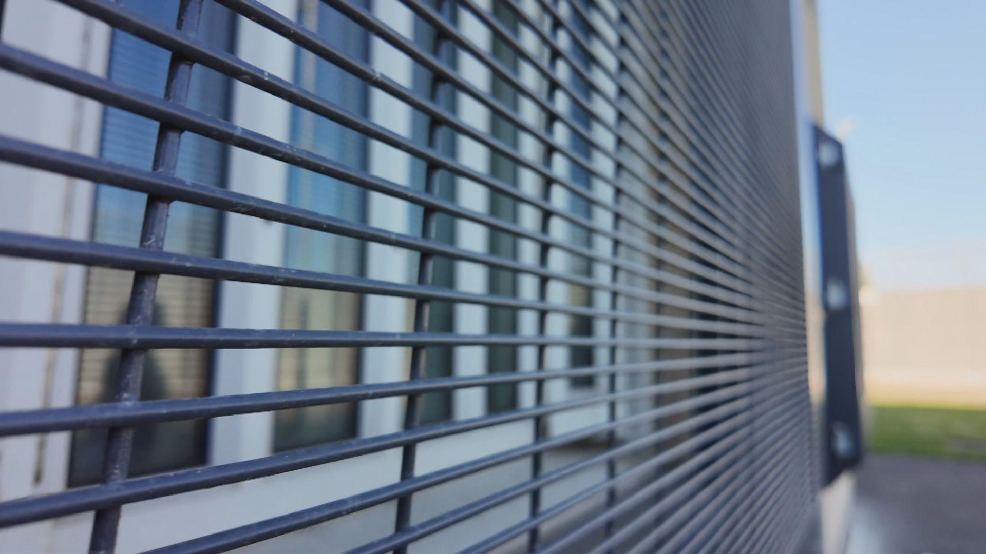 A close-up image of a black meta grille fitted over a window at Perth prison. In the distance, other windows show the same grilles.