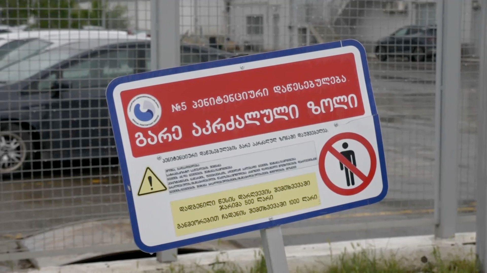 A close up picture of a warning sign outside of a Georgian prison. The sign is entirely in Georgian with a warning sign for prohibited access.