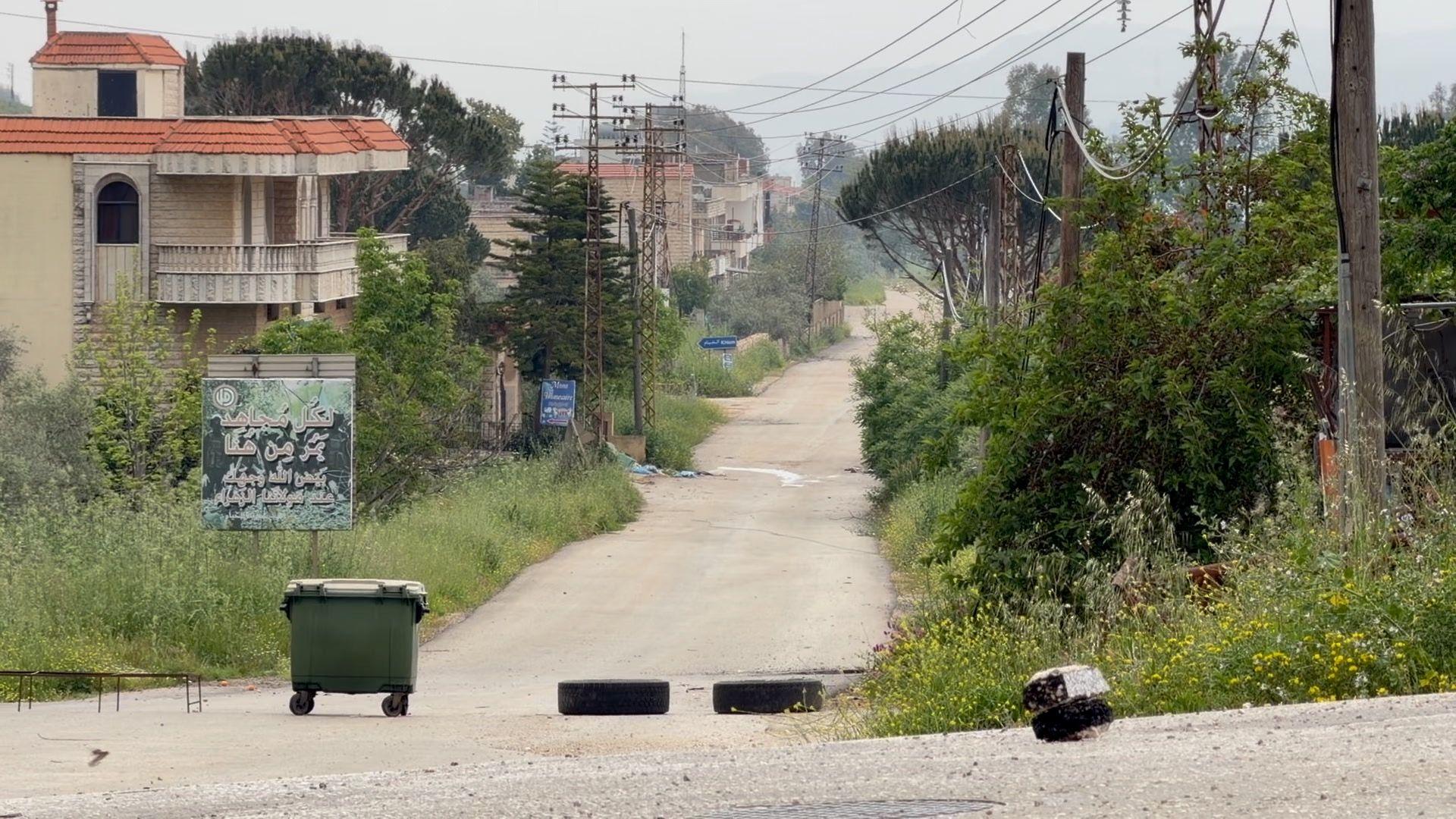 Një kosh i madh mbeturinash dhe dy goma në një rrugë të zbrazët në Libanin jugor, pranë territorit të pushtuar nga forcat izraelite