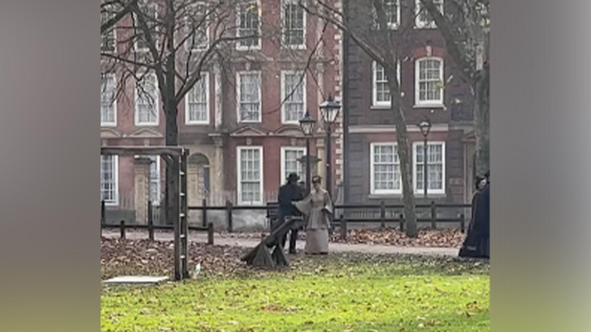 Two people in period dress stand together in Queen Square in Bristol