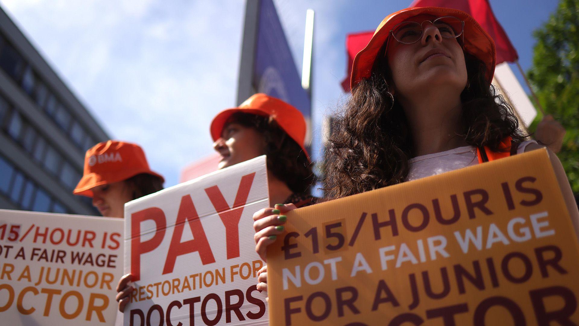 Junior doctors striking holding up orange signs calling for a fair wage and pay restoration for doctors