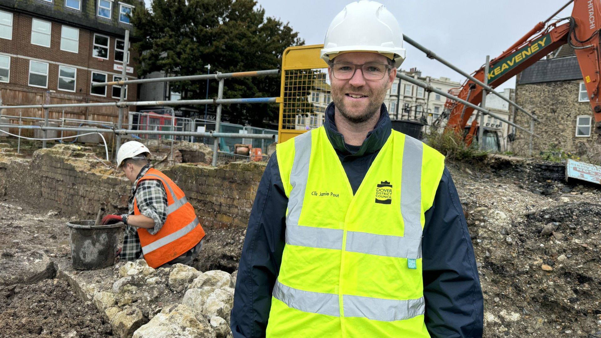 Jamie Pout, the deputy leader of Dover District Council, standing facing the camera wearing hi vis and hard hat
