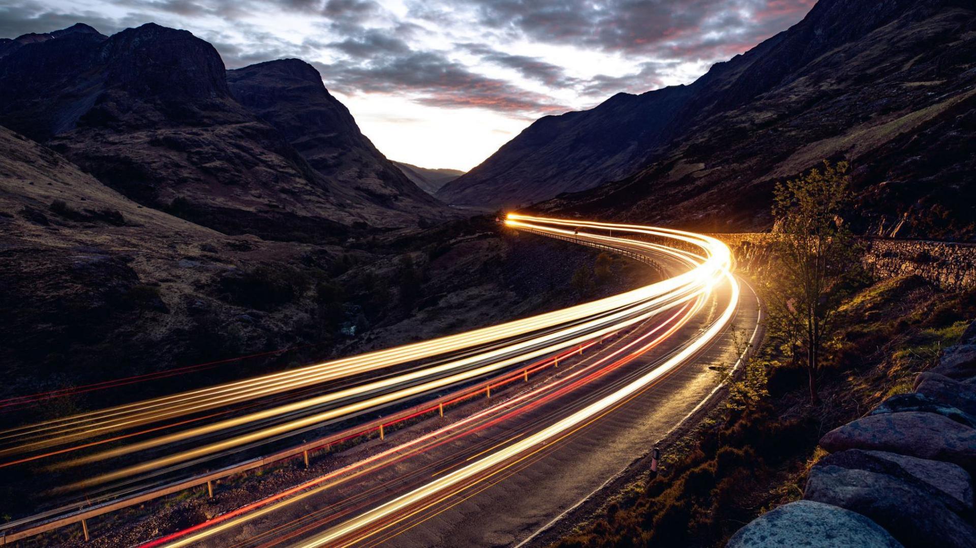 Light trails left by a vehicle in the night on a road in the Highlands.