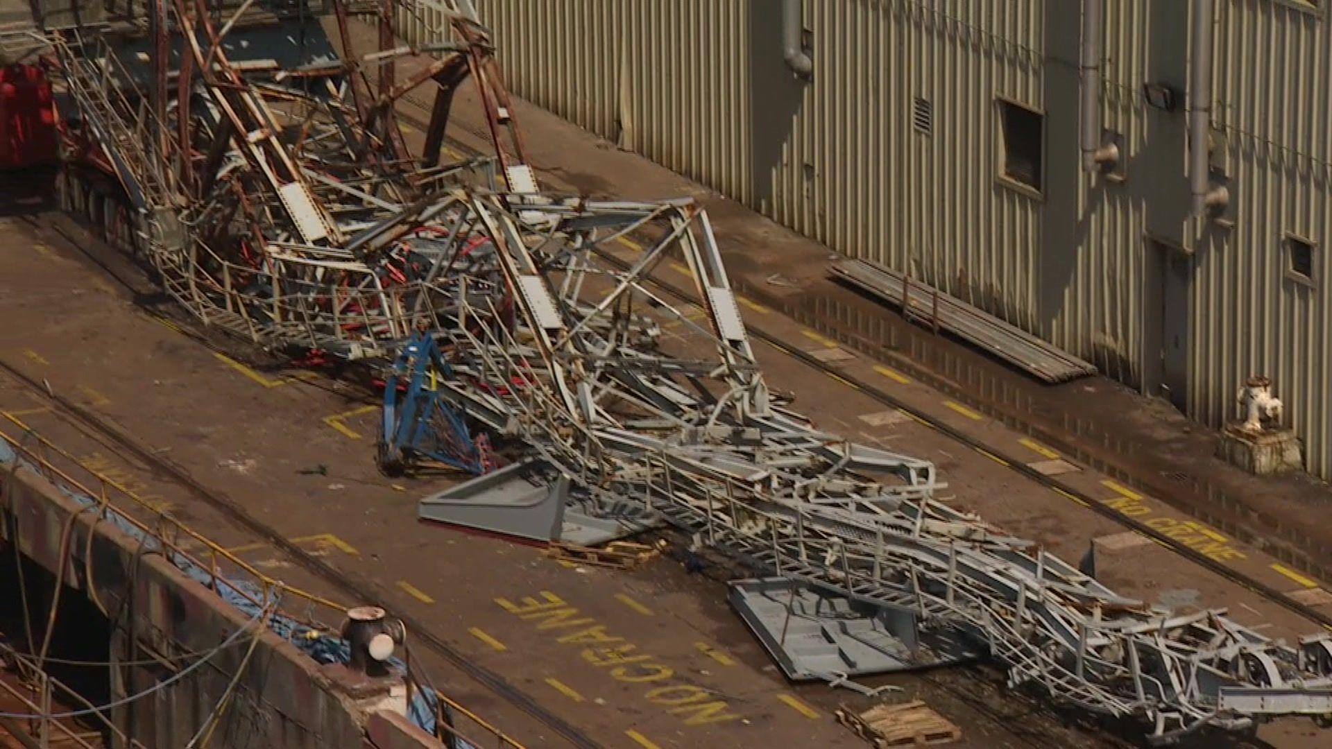 The aftermath of the crane collapse. The metal crane fell next to a boat and there are pieces of metal all around the area.