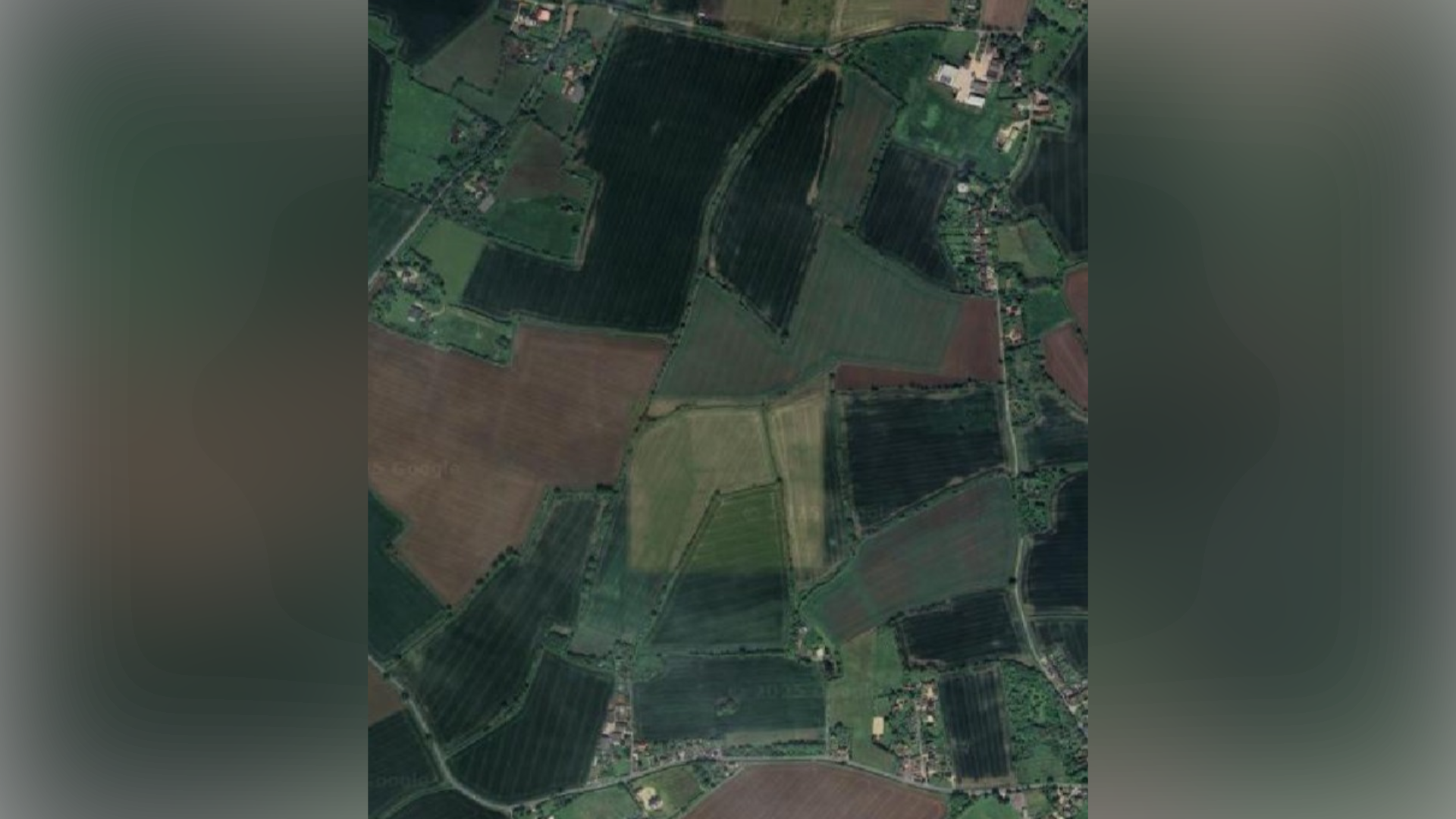 An aerial view of farmland where the solar farm could be built. Some rural villages and roads can be seen around the fields.