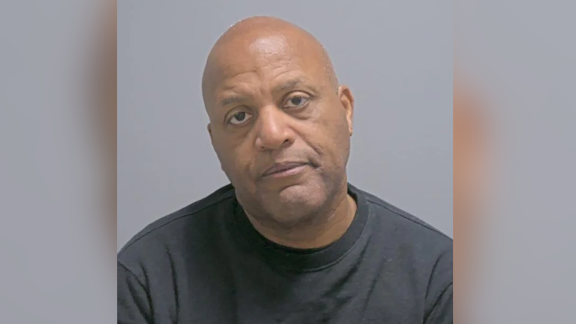 Raymond Williams a man who is sitting down having his picture taken. He is bald and is wearing a black sweatshirt. He is looking directly at the camera.