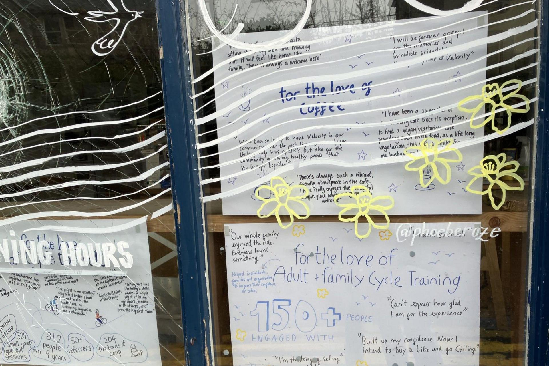 Messages on the posters include celebrations of work done by Velocity with adults and families. One of the posters has the words: "For the love of coffee". Stencilled on the window are wavy lines, a bird and yellow daffodils. 