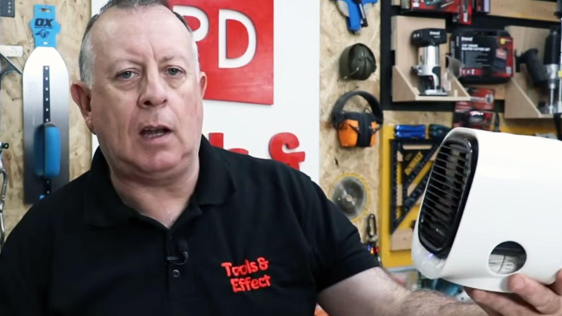 Stuart Matthews in a grab from his You Tube channel Proper DIY in a black t shirt holding the white cube fan