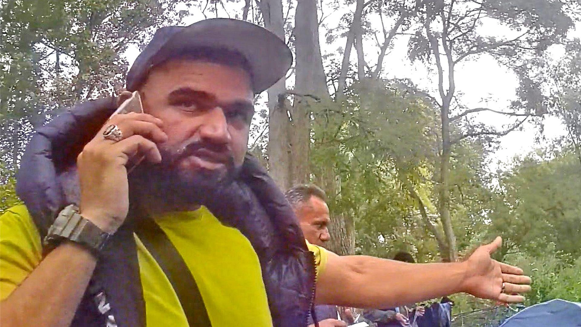 Abdullah the smuggler, in a forest clearing, with people in the background behind him.