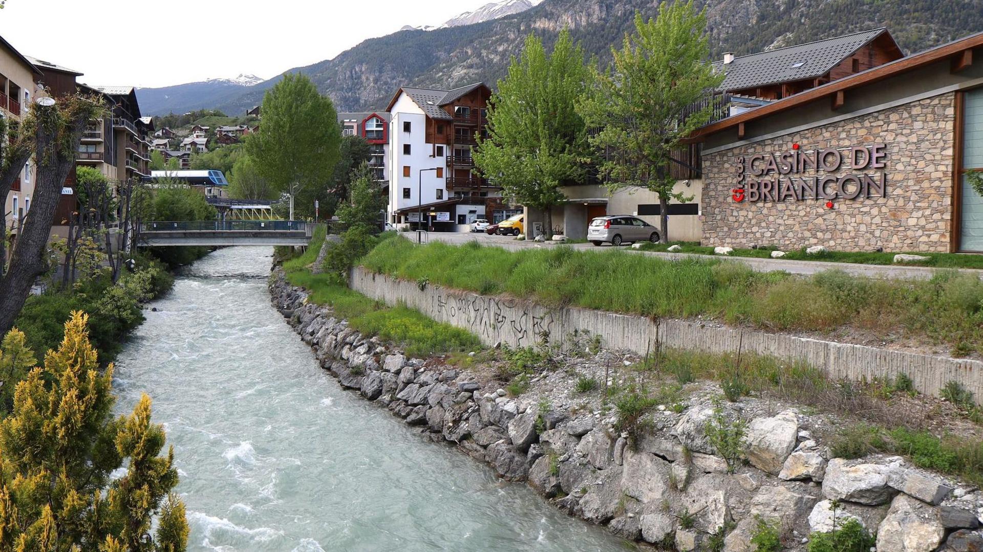 The river Guisane cuts through the French commune of Briancon. On one back a casino can be seen, in the background the Alps rise to the sky.