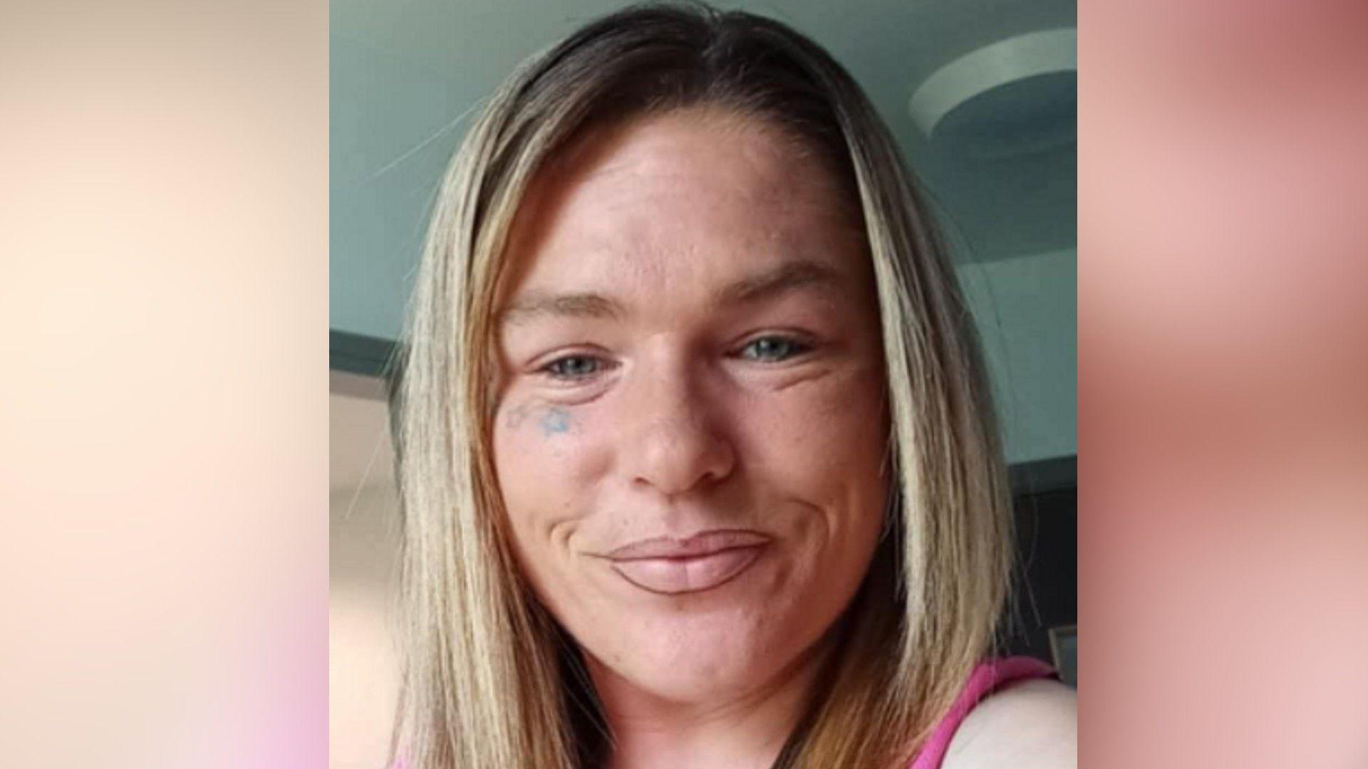 A woman with long blond hair, she is smiling and has a star tattoo under her left eye.