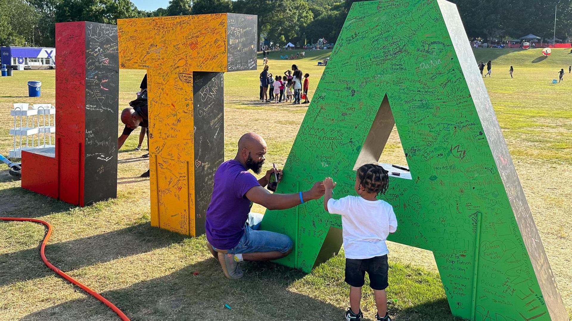 Torino Henry signs an art installation at Atlanta's Juneteenth celebration