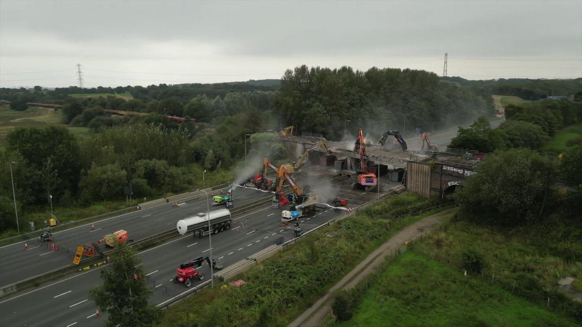 Bulldozers start to bring down sections of the motorway bridge