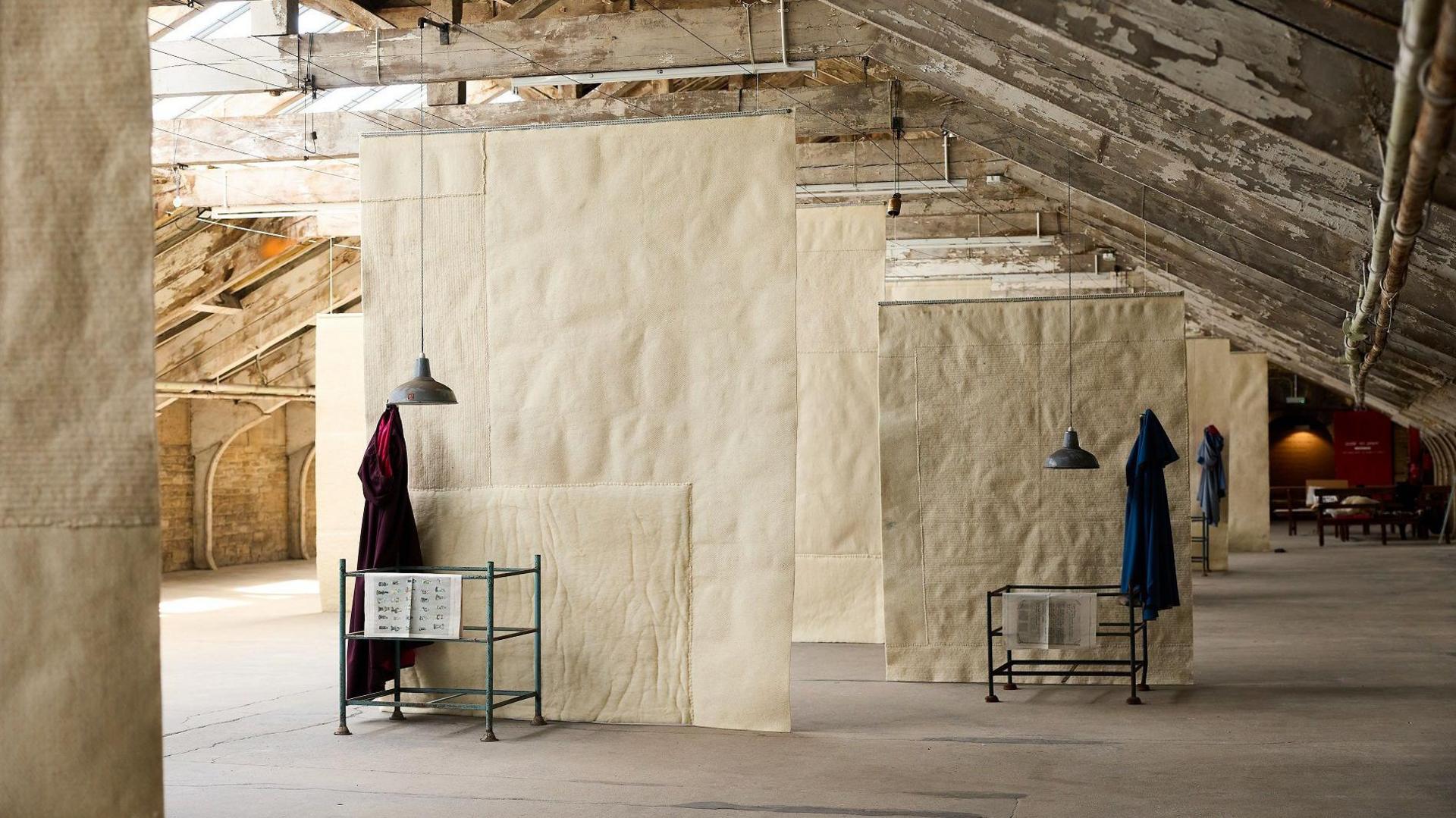 A mill room with wooden rafters and hanging fabrics