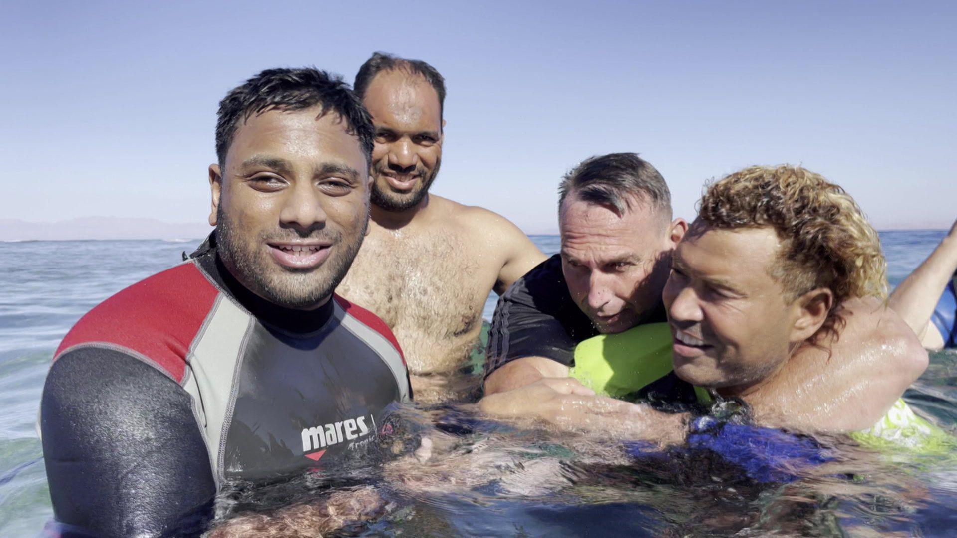 Mohammed Salim Patel and Shaun Gash in the sea with their instructors after completing the 40m diving challenge