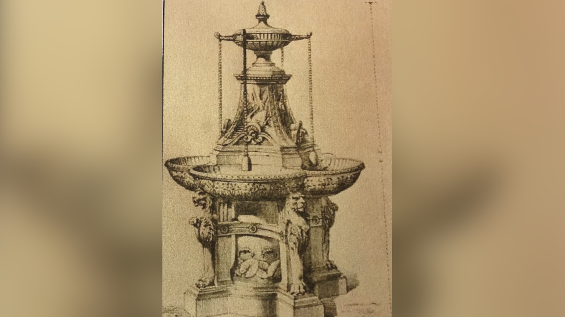 Black and white drawing of an ornate cast iron water feature with drinking fountain and four cups on chains hanging just above four troughs and small spouts. The structure sits on a plinth with lions heads on four supporting pillars. It stands around 2m (6ft) tall and is about 1m (3ft) in diameter.