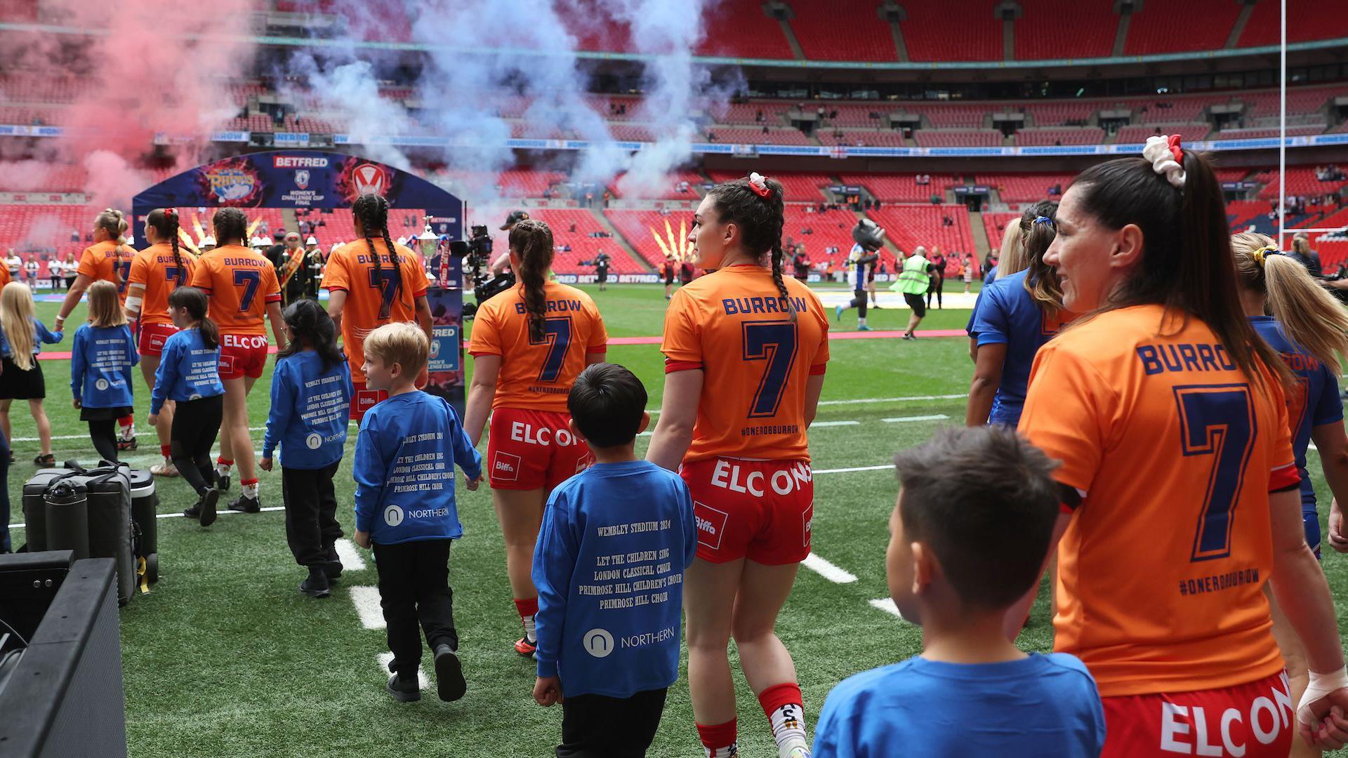 St Helens players filter out of the tunnel and onto the Wembley turf surrounded by young mascots for the 2024 women's Challenge Cup final